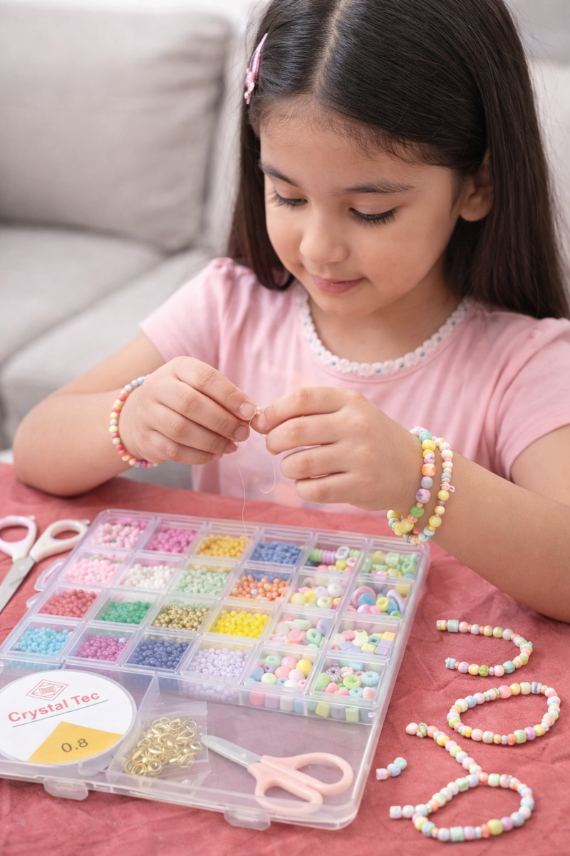 Child making a bead necklace with a kit on a pink surface