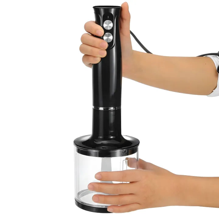 Handheld blender with clear container held by a person on a white background