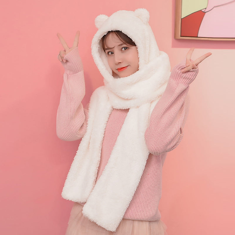 Person wearing a white bear hood and scarf against a pink background