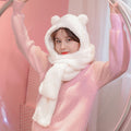 Person wearing a pink sweater and white bear-themed hooded scarf against a pink background