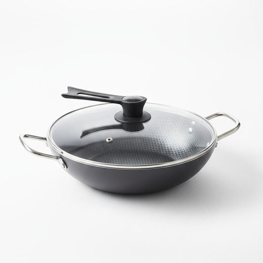 Black wok with a transparent lid on a white background