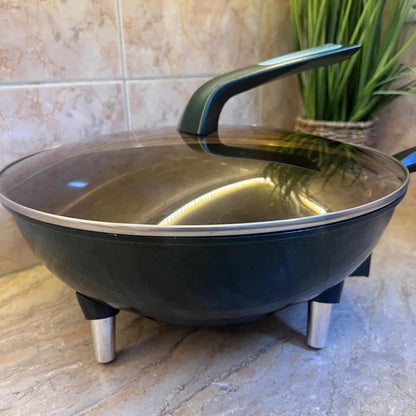 Black frying pan with glass lid on a tiled floor