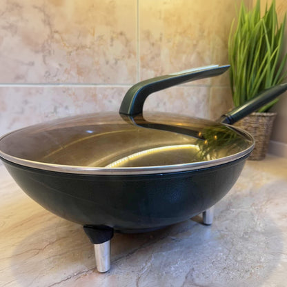 Black wok with a lid on a tiled floor