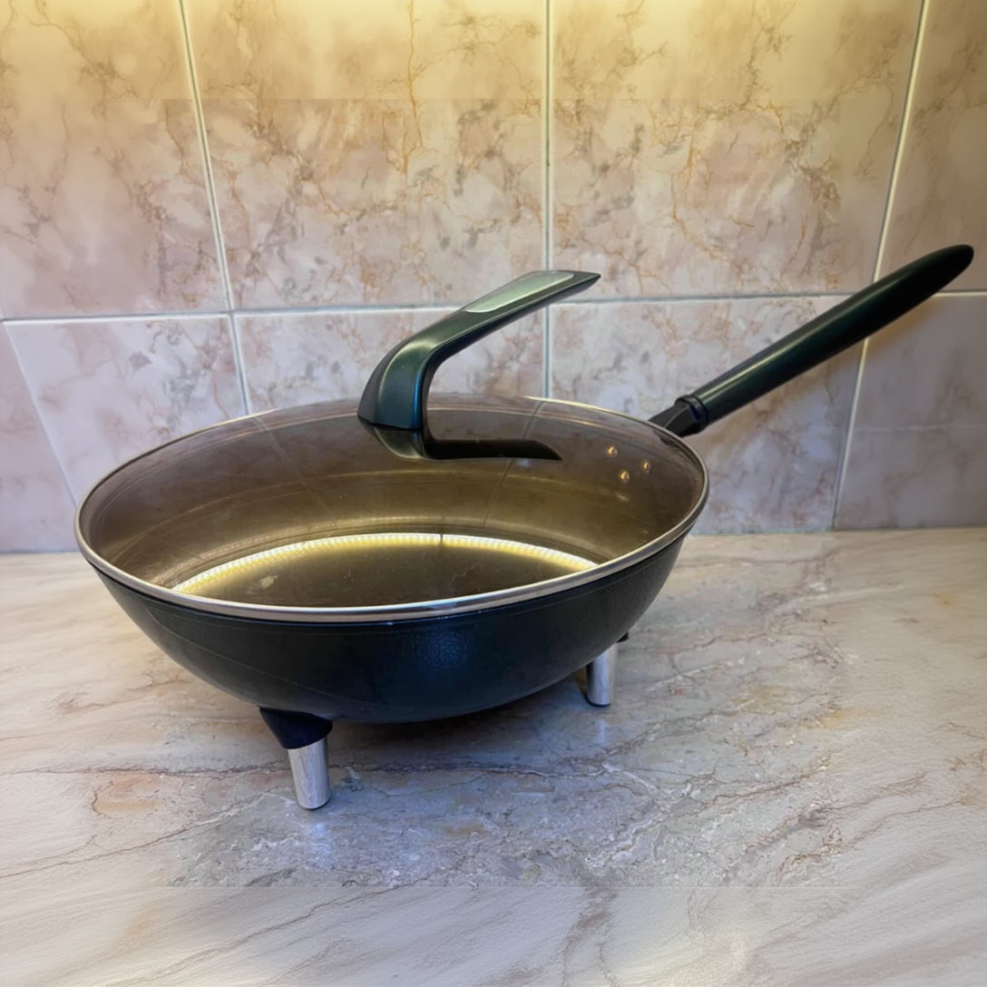 Black frying pan with a handle on a tiled floor