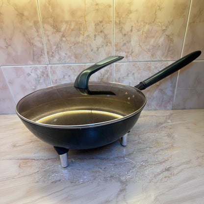 Black frying pan with a handle on a tiled floor