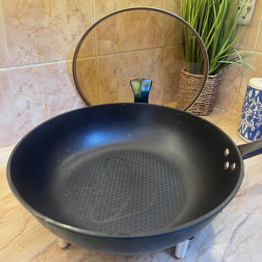 Black frying pan on a tiled kitchen counter with a plant in the background