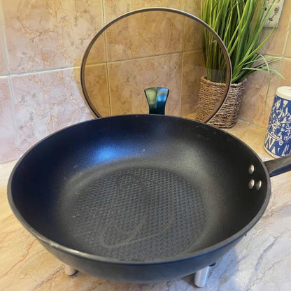 Black frying pan on a tiled kitchen counter with a plant in the background