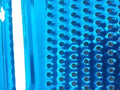 Close-up of a blue rectangular kitchen tool with a series of evenly spaced small, circular indentations in a grid pattern. The surface has a slightly glossy, reflective appearance with a vertical white light reflecting along the left edge, reminiscent of a sleek Techmanistan 3in1 Stainless Steel Vegetable Slicer Chopper Grater.